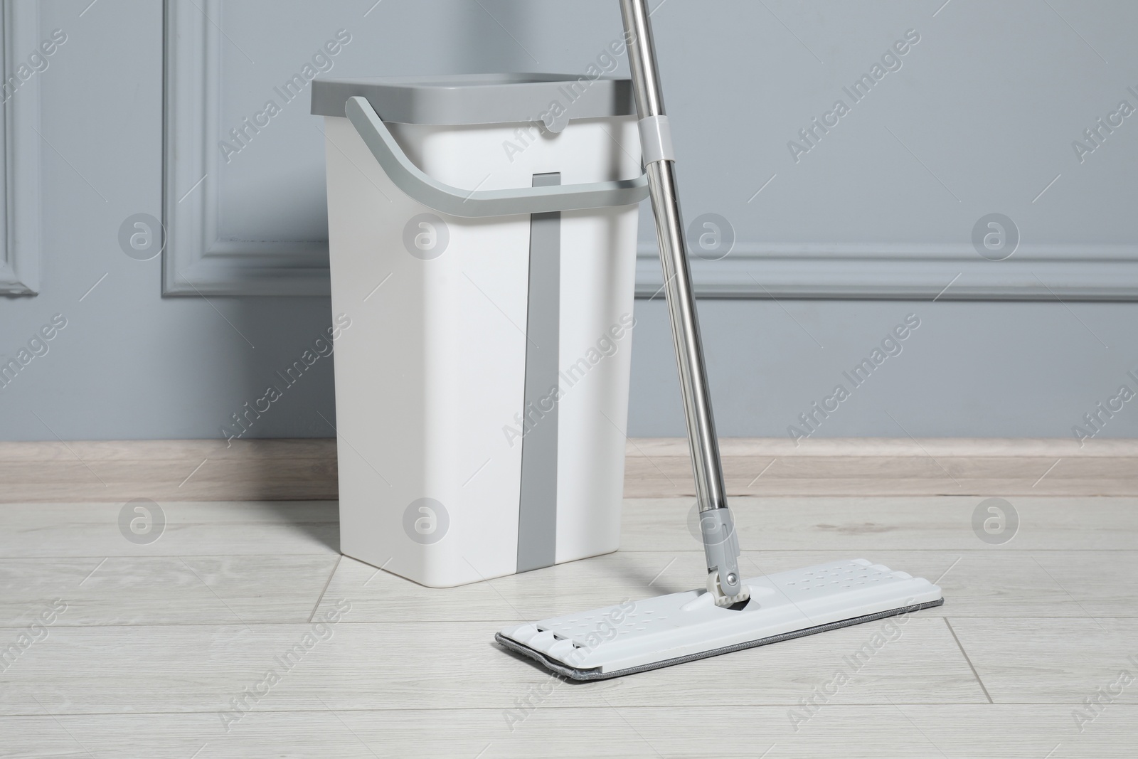 Photo of Mop and bucket on parquet indoors. Cleaning floor