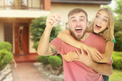 Image of Dream home. Happy couple with key near their big beautiful house. Space for text