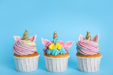 Three cute sweet unicorn cupcakes on light blue background