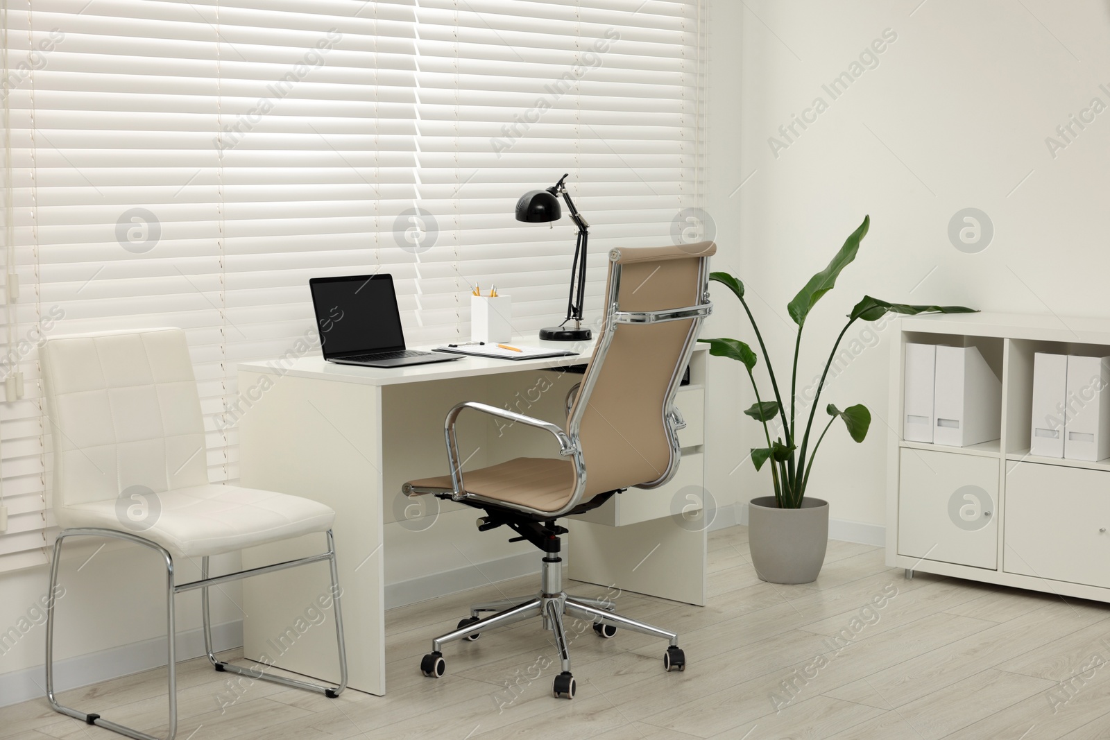 Photo of Doctor's workplace. Chairs, laptop and clipboard on table in clinic