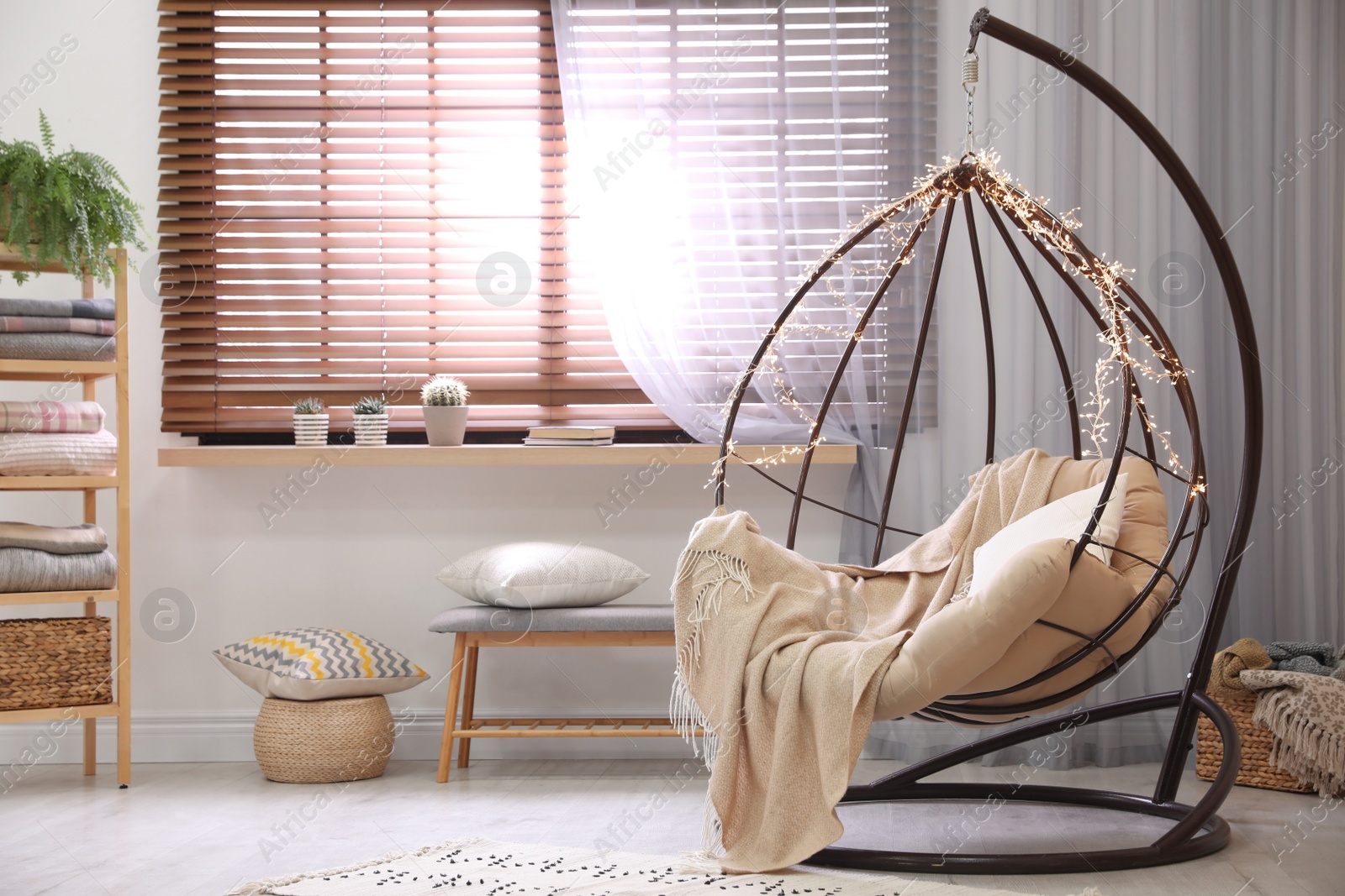 Photo of Cozy hanging chair with fairy lights in modern living room. Interior design