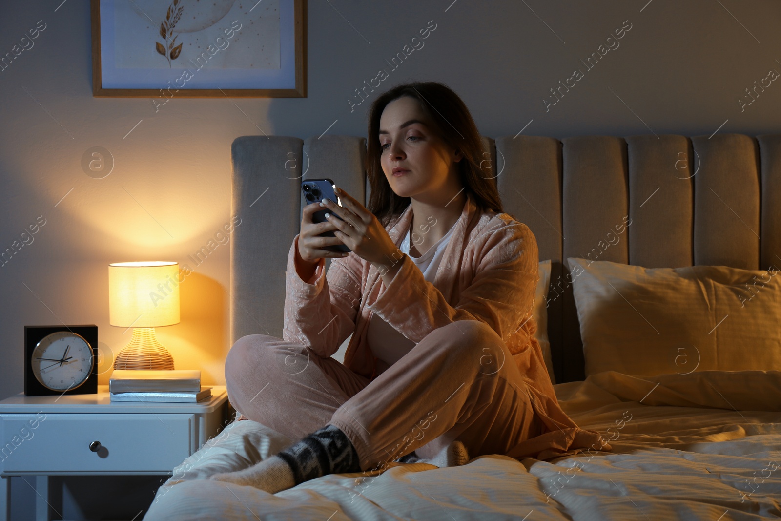 Photo of Woman using smartphone on bed at night. Internet addiction