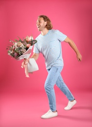 Photo of Young handsome man with beautiful flower bouquet on pink background