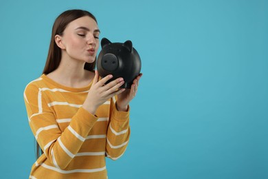 Woman with piggy bank on light blue background, space for text