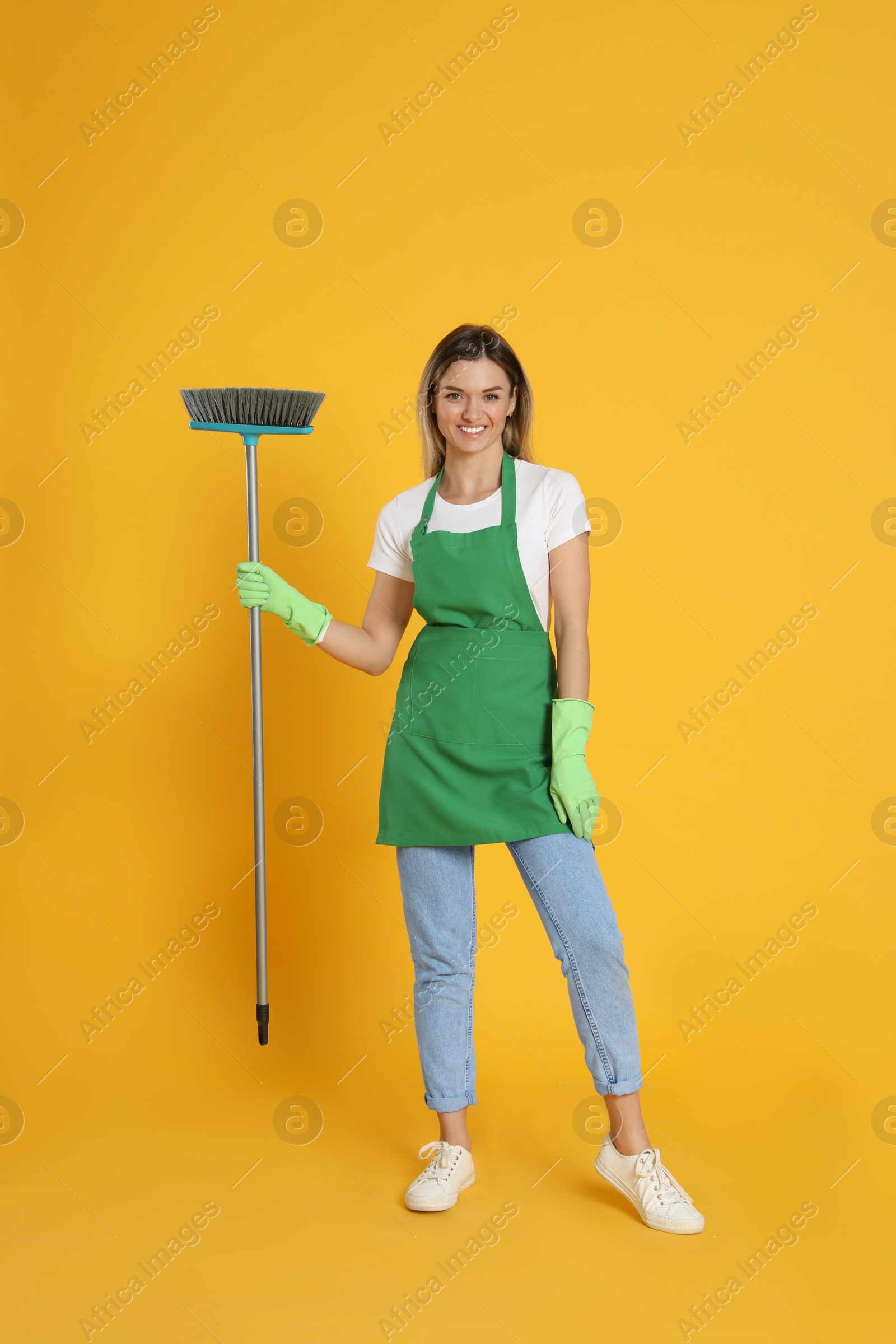 Photo of Young woman with broom on orange background