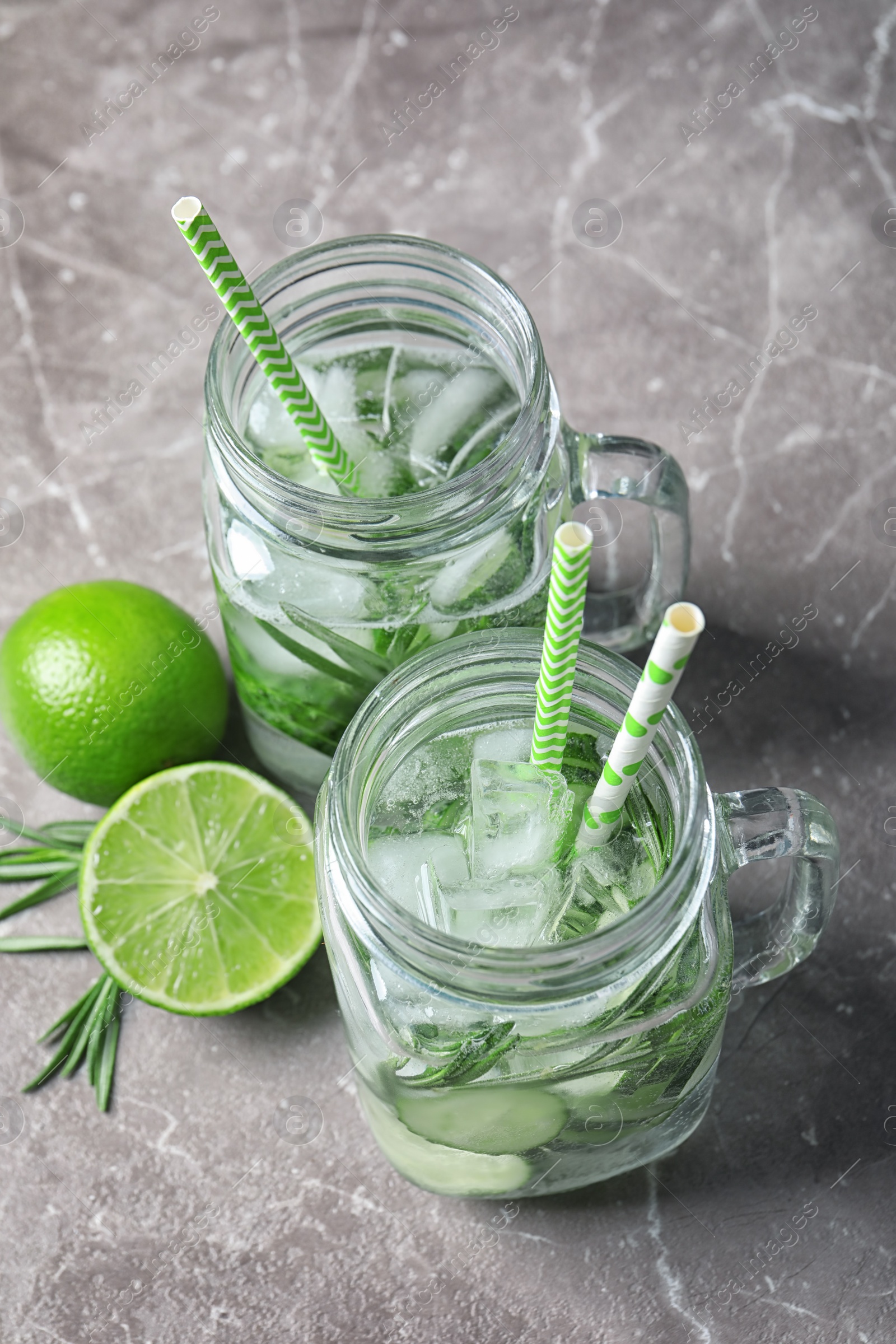 Photo of Natural lemonade with cucumber, lime and rosemary in mason jars on table