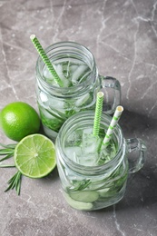 Natural lemonade with cucumber, lime and rosemary in mason jars on table