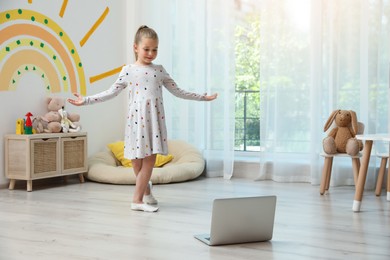 Photo of Cute little girl taking online dance class at home