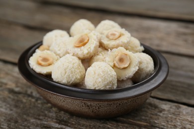 Photo of Delicious candies with coconut flakes and hazelnut on wooden table, closeup