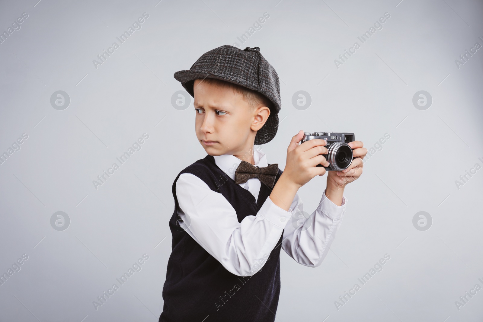 Photo of Cute little detective with vintage camera on grey background