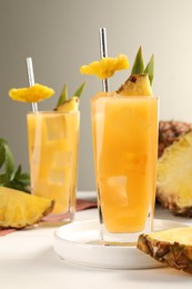 Tasty pineapple cocktail and sliced fruit on white table