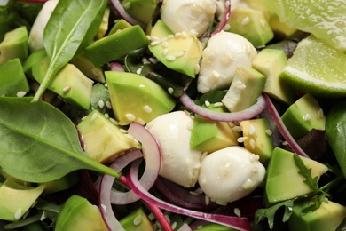 Photo of Delicious avocado salad with mozzarella as background, closeup