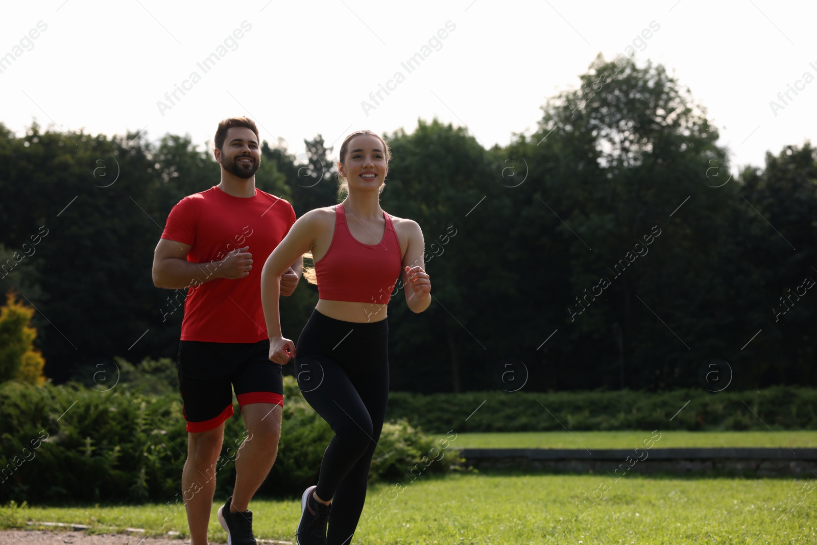 Photo of Healthy lifestyle. Happy couple running outdoors on sunny day, space for text