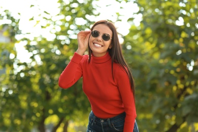 Photo of Beautiful woman wearing stylish sunglasses in green park