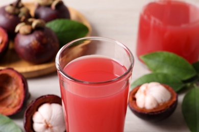 Photo of Delicious mangosteen juice in glass on table, closeup