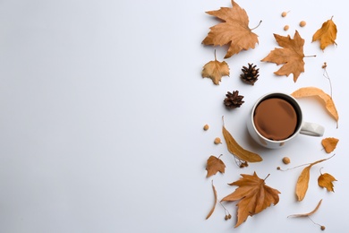 Flat lay composition with cup of hot drink and autumn leaves on white background, space for text. Cozy atmosphere