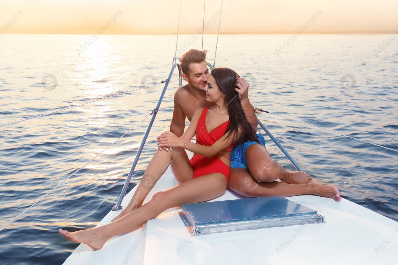 Photo of Young man and his beautiful girlfriend in bikini on yacht. Happy couple during sea trip