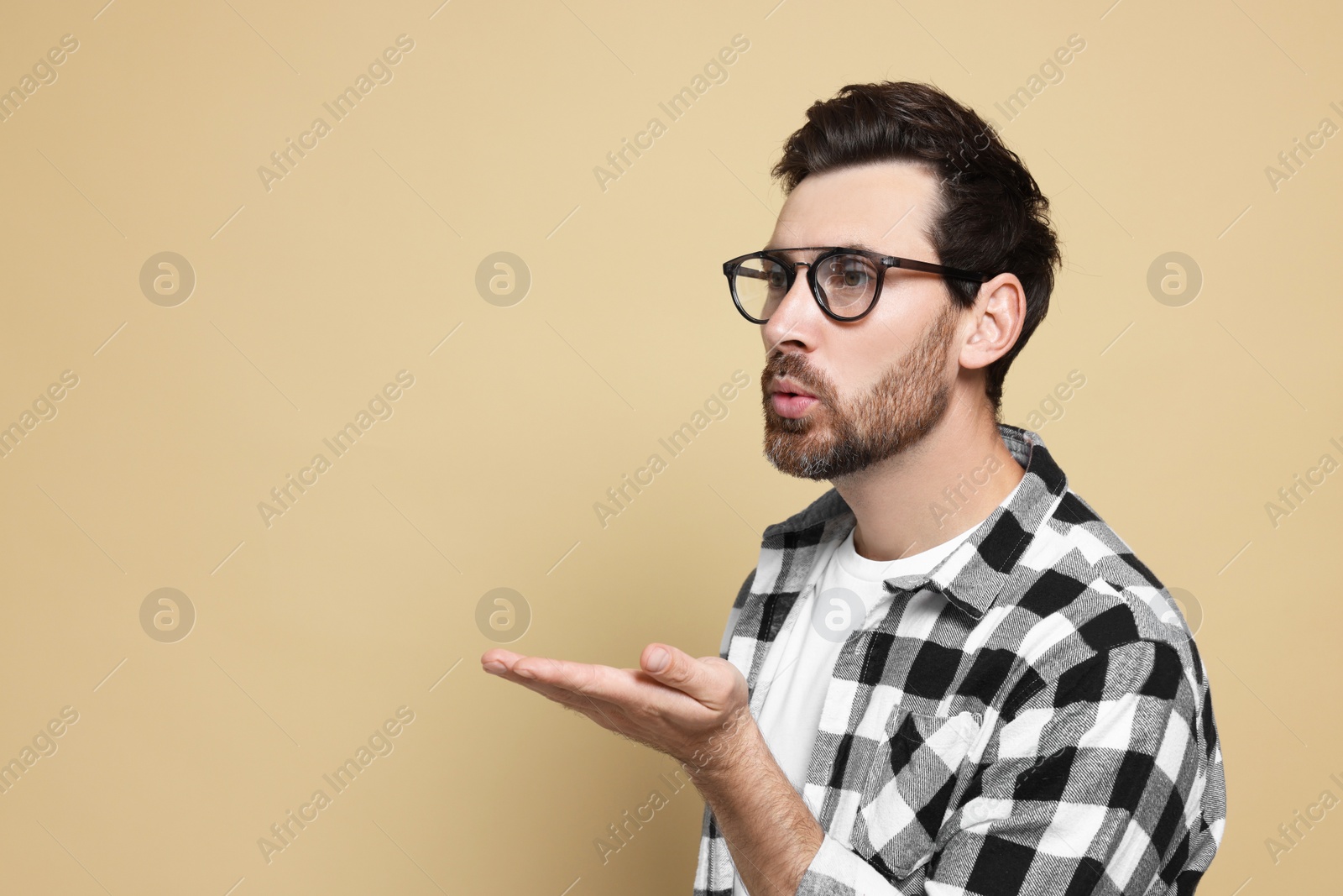 Photo of Handsome man blowing kiss on beige background. Space for text