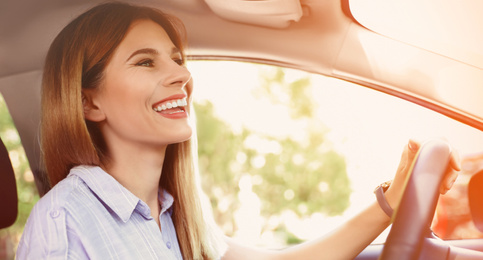 Happy woman driving modern car on sunny day