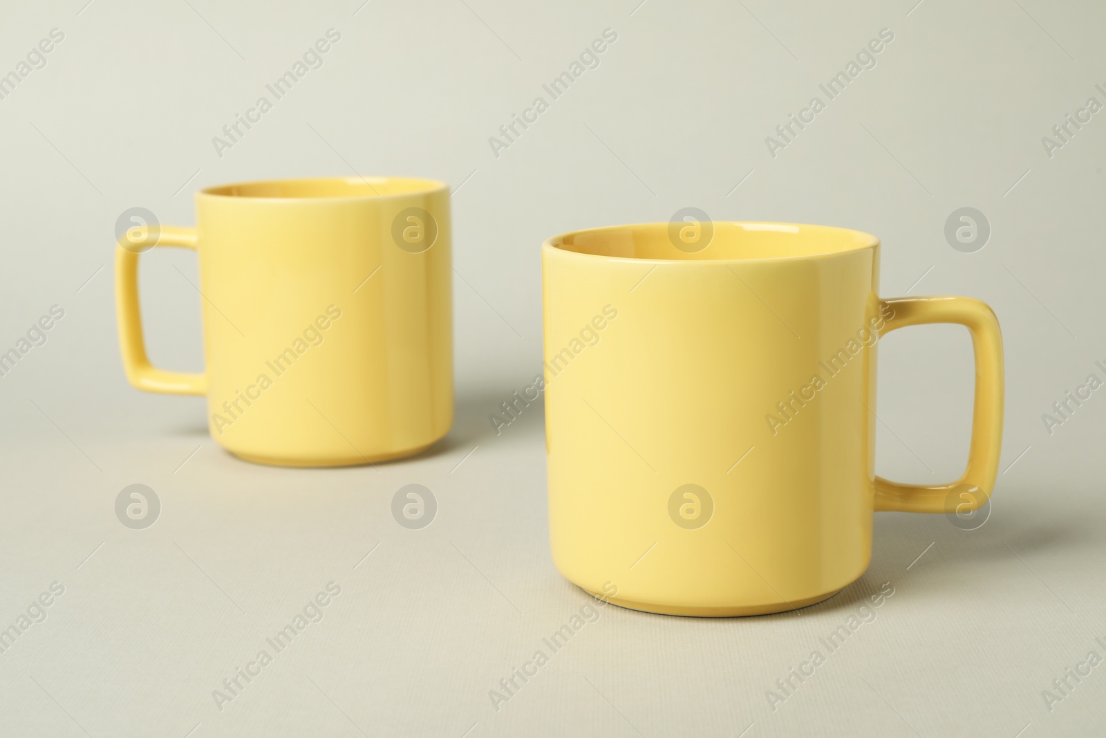 Photo of Two yellow ceramic mugs on light grey background