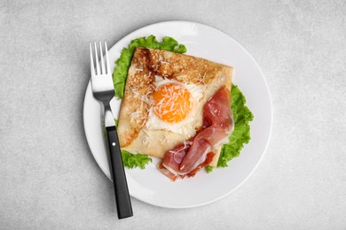 Photo of Delicious crepe with egg served on light gray table, flat lay. Breton galette