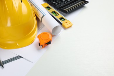Photo of Construction drawings, safety hat, calculator, tape measure and bubble level on white background. Space for text