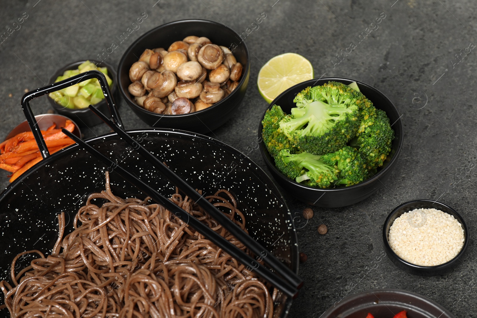 Photo of Wok with noodles, chicken and other products on grey table