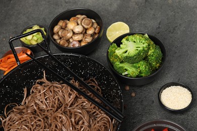 Photo of Wok with noodles, chicken and other products on grey table