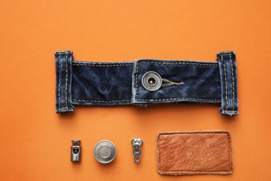 Photo of Flat lay composition with garment accessories and cutting details for jeans on orange background