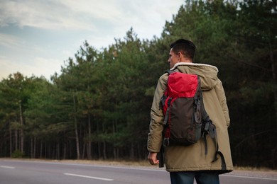 Photo of Man with backpack on road near forest, back view