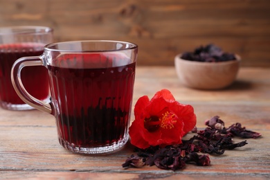 Photo of Delicious hibiscus tea and dry flowers on wooden table