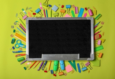 Photo of Flat lay composition with different school stationery and small chalkboard on color background