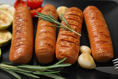 Photo of Delicious grilled sausages with rosemary on dark plate, closeup
