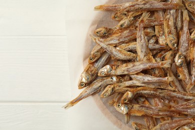 Photo of Tasty dried anchovies on white wooden table, top view. Space for text