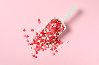 Photo of Heart shaped sprinkles and scoop on pink background, flat lay