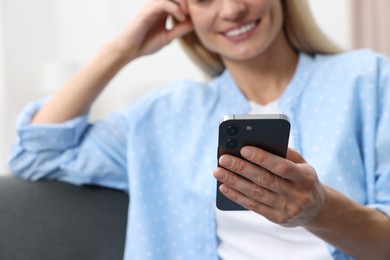 Photo of Happy woman sending message via smartphone at home, closeup