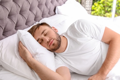Photo of Young handsome man sleeping in bed at home. Early morning