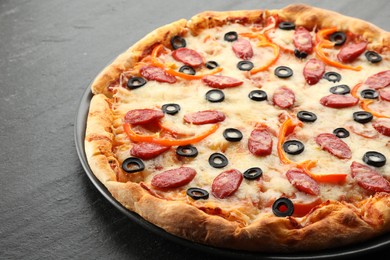 Photo of Tasty pizza with cheese, dry smoked sausages, olives and pepper on grey table