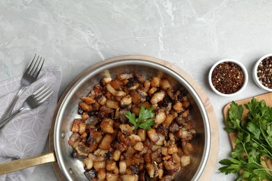 Photo of Tasty fried cracklings on light marble table, flat lay. Cooked pork lard
