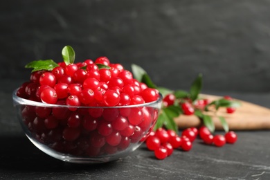 Photo of Fresh cranberry in bowl on dark grey table, space for text