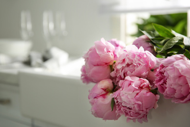 Bouquet of beautiful pink peonies on counter in kitchen. Space for text