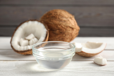 Photo of Coconut oil in bowl on white wooden table
