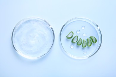 Photo of Cut aloe vera and cosmetic gel on light blue background, top view