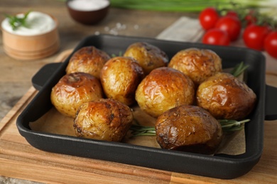Photo of Delicious hot baked potato with sour cream on wooden table