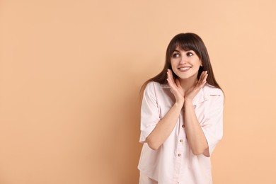 Photo of Happy woman wearing pyjama on beige background