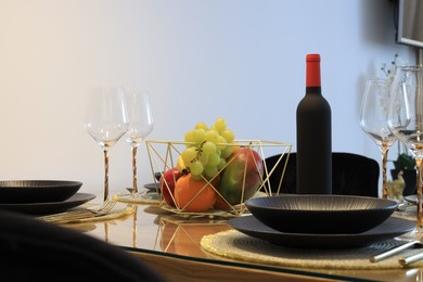 Photo of Bottle of wine and fruits on table served for dinner indoors