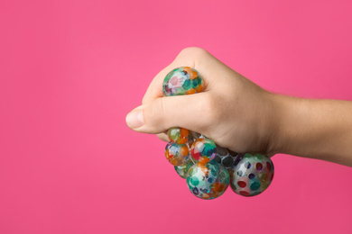 Photo of Woman squeezing colorful slime on pink background, closeup. Antistress toy