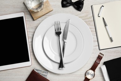 Photo of Business lunch concept. Plates, cutlery, glass of water, tablet and notebook on wooden table, flat lay