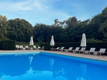 Photo of Outdoor swimming pool in luxury hotel on sunny summer day. Time for relax