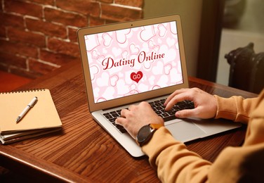 Image of Man visiting dating site via laptop at wooden table indoors, closeup